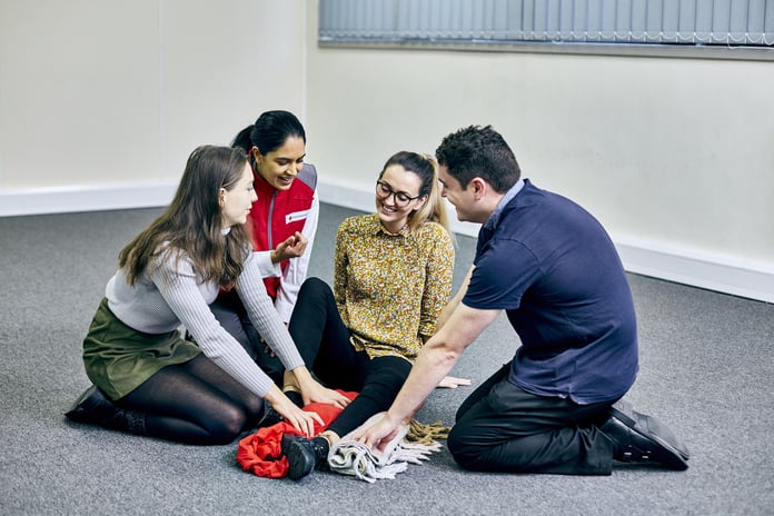 A trainer and three colleagues at a British Red Cross training course, running through a potential on site hazard.